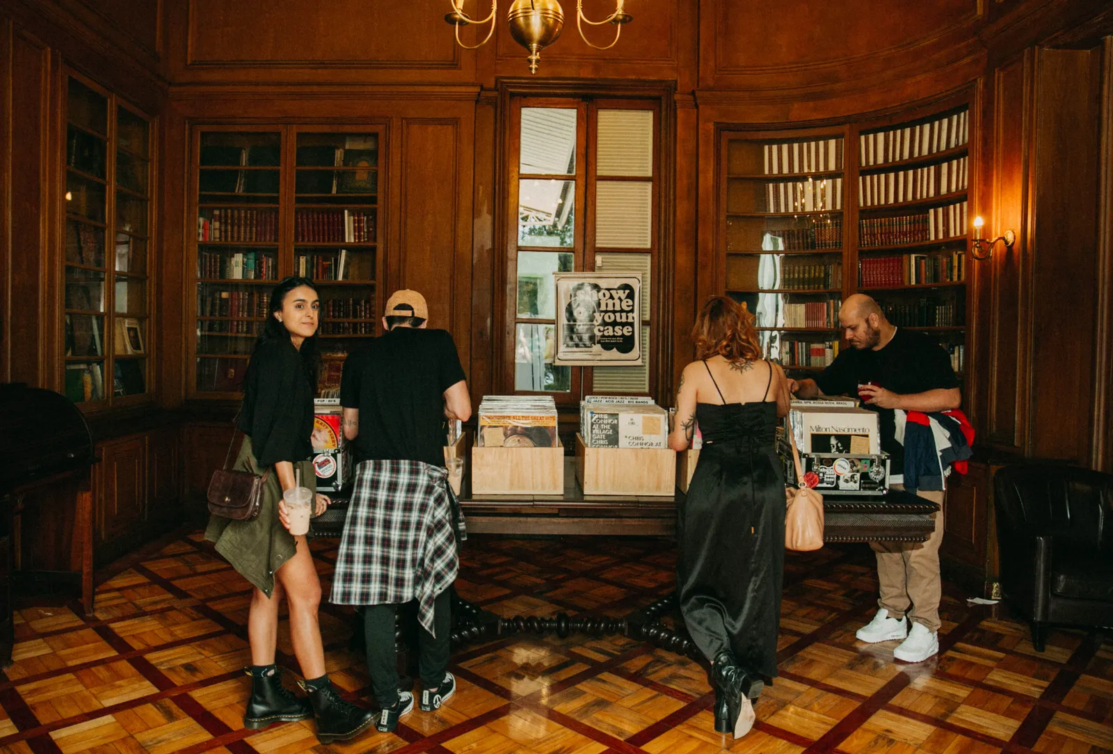 Sequência de ambientes da biblioteca e salões históricos do Nacional Club com feira de vinil, apresentações musicais, encontros entre visitantes e espaços de convivência. A imagem mostra a diversidade de experiências oferecidas pela Jazz Mansion.