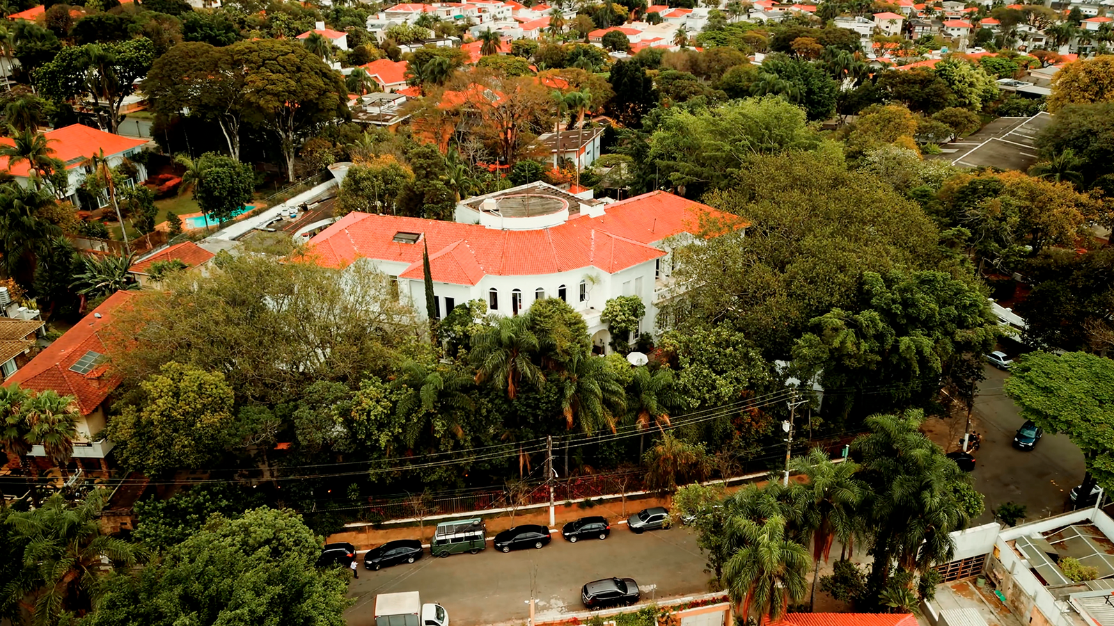 Vista aérea do Nacional Club cercado por árvores e ruas residenciais no bairro do Pacaembu, em São Paulo. A imagem apresenta o patrimônio histórico que abriga a Jazz Mansion e evidencia a integração da arquitetura com a área verde.