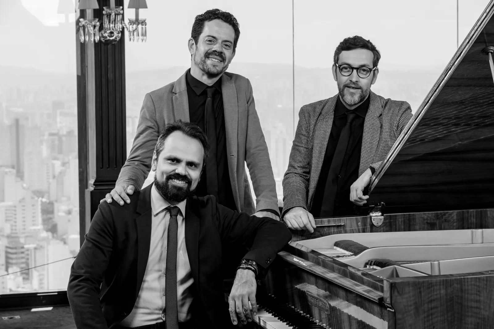 Três integrantes do Living Room Jazz junto a um piano.