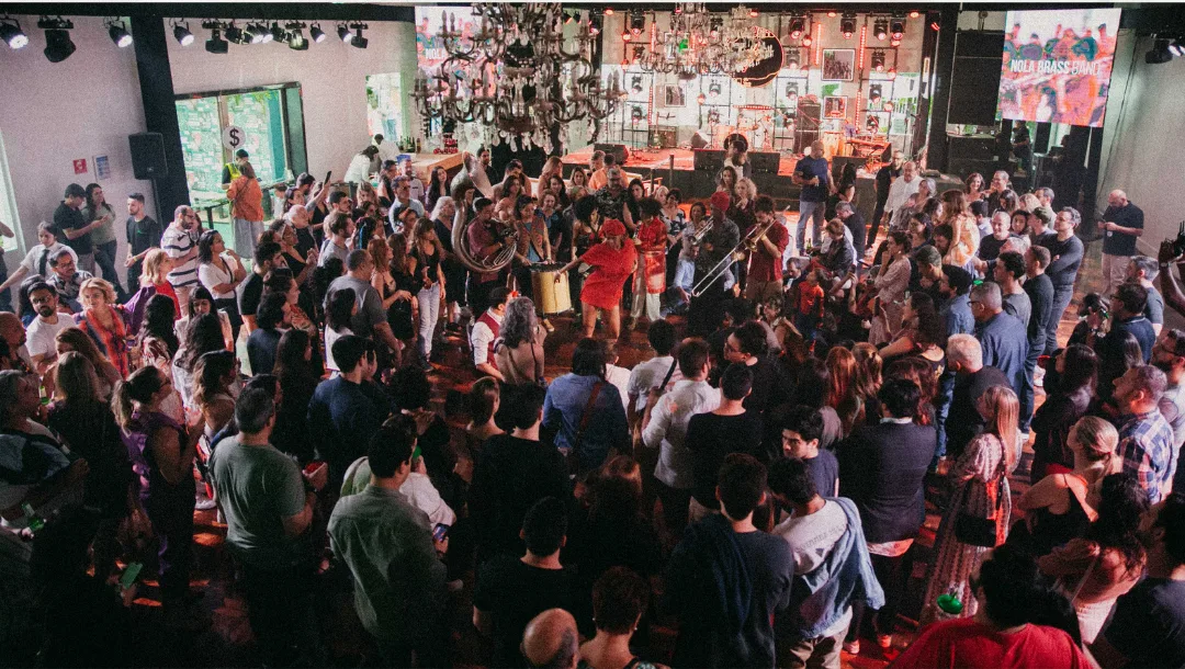Público em volta de uma brass band no meio do salão, num evento da Jazz Mansion